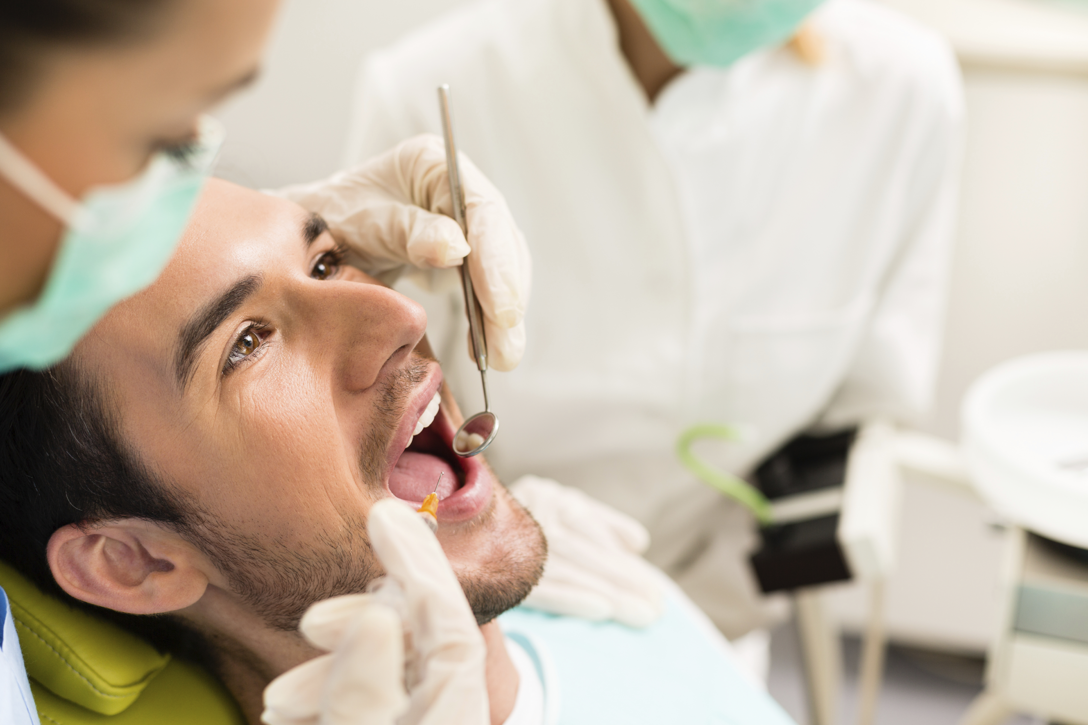Признаки лечения зубов. Стоматолог. Человек у стоматолога. Стоматолог мужчина.